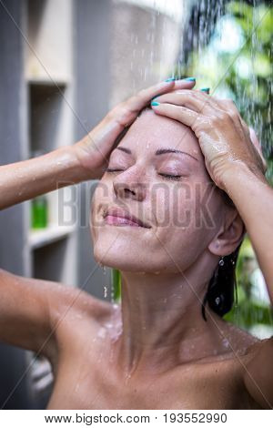Beautiful naked young woman taking shower in bathroom outside on he luxury villa. Tropical Bali island.