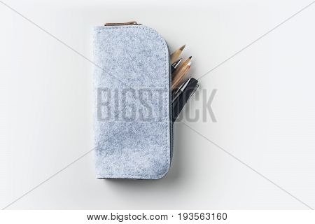 Top view of grey fabric pencil case with lot of pens on white background desk for mockup