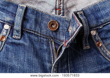 Unbuttoned zipper on old blue jeans. Background and texture