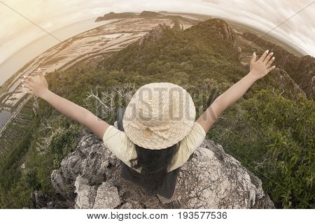 Funny female traveler with hat sitting on top of a mountain and enjoying , freedom viewpoint of Thailand.