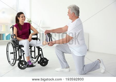 Young disabled woman with senior orthopedist in rehabilitation clinic