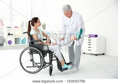 Young disabled woman with senior orthopedist in rehabilitation clinic