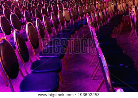 Colored chairs in the cave before the concert. Chairs in the concert hall. Empty rows of red seats in cave.