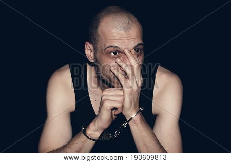 Man with handcuffs. Arrested criminal. Isolated on black background.