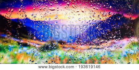 mountains and field of flowers A view of the city from a window from a high point during a rain. Rain drops on glass. Focus on drops