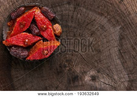 Sweet Dessert Baklava with hazelnut on silver tray. Top view of Turkish pakhlava and dry dates on wooden rustic stump. Copy space.