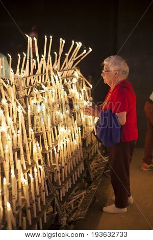 El Rocio Spain - June 2 2017: Female pilgrim lights up candles in the hermitage of El Rocio during the Romeria 2017. Andalusia Spain