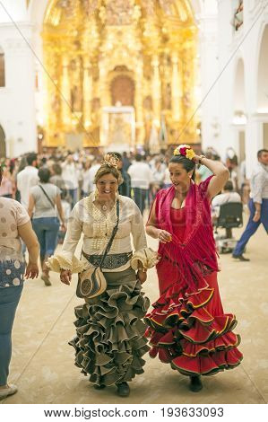 El Rocio Spain - June 2 2017: Pilgrims in traditional spanish flamenco dress in the hermitage of El Rocio during the Romeria 2017. Andalusia Spain