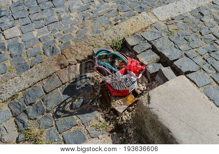 Exposed and unprotected electrical wiring on a cobbled pavement or street
