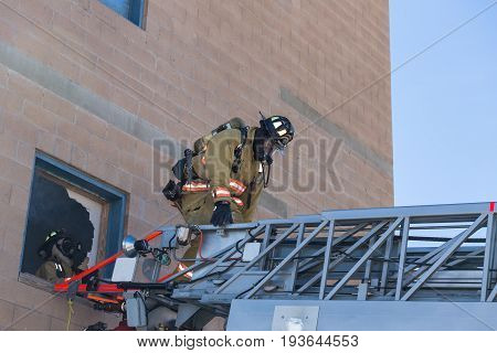 Firefighter Training Entering And Exiting A Building On A Truck Ladder