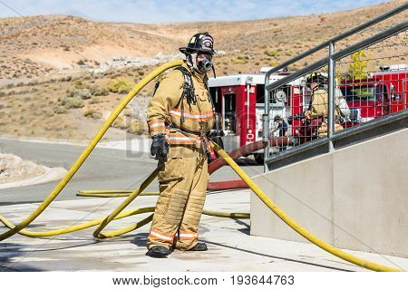 Firefighter Training Entering A Building With A Charged Hose