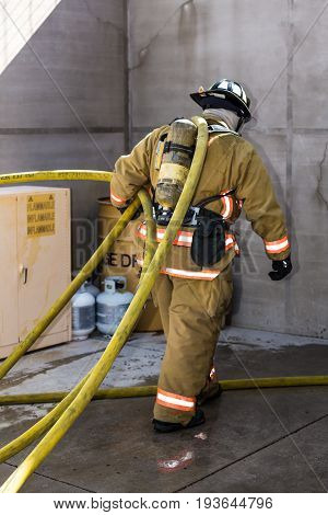 Firefighter Training Entering A Building With A Charged Hose