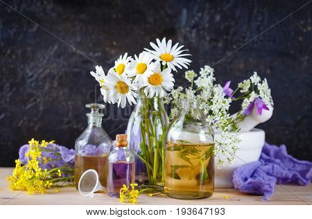 Mortar with fresh wild flowers and essential oil in glass bottles. Herbal medicine.