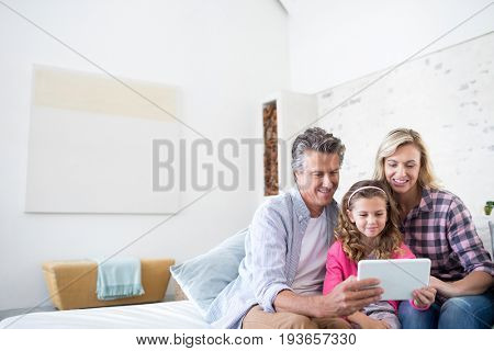 Smiling family using digital tablet together in living room at home