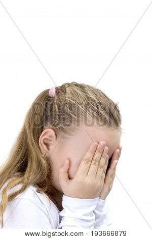 Child covering her face with her hands. Blonde little girl covers her face with her hands isolated. Girl hide face under hands playing hide-and-seek