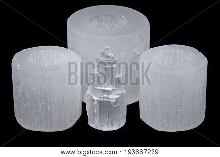 White selenite cylinder tea light holders and everest carving on black background