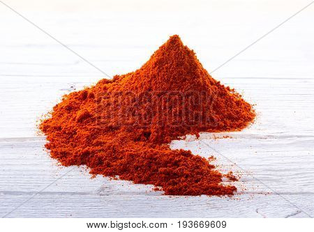 Heap of bell pepper sweat paprika powder on white wooden background.