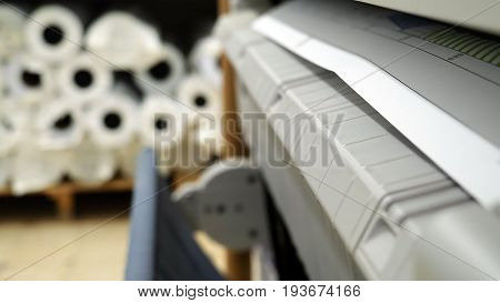 Wide format printer is printing color design draft outline sketch drawing in the printing house. Design office supply equipment.