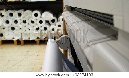 Wide format printer is printing color design draft outline sketch drawing in the printing house. Design office supply equipment.