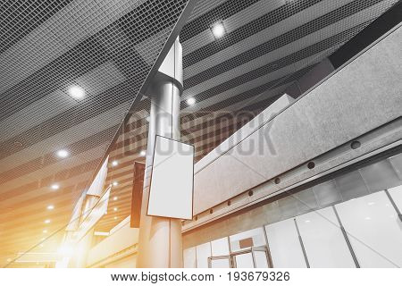 Wide angle view of Information vertical LCD screen or TV in mall interior blank white poster mock-up in hall of airport terminal empty rectangular billboard on the column indoors of modern building
