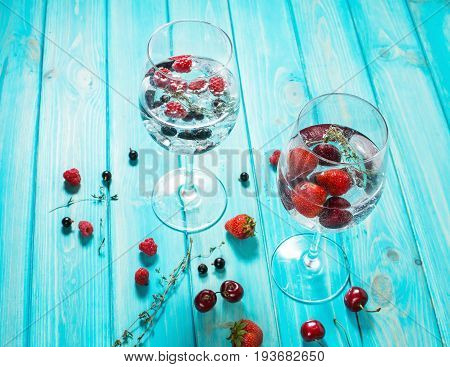 Refreshing cocktail with vodka martini with ice and berries on wood table.