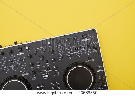 Flat lay of part of  mixing board on yellow background. Musical device lying catty-corner, close-up shot