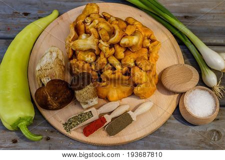 Chanterelle mushrooms and boletus edulis with ingredients for cooking on wooden plate