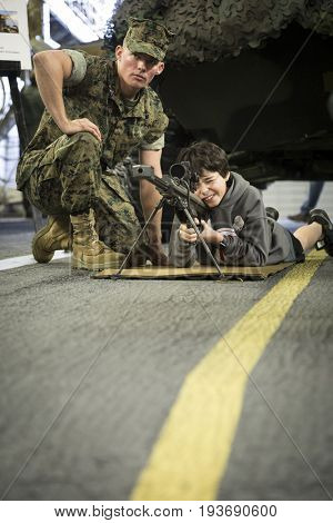 Ship Tour USS Kearsarge (LHD 3) Wasp-class amphibious assault ship: US Navy personnel helps an unidentified boy take aim through the rifle scope of SASR sniper rifle. Fleet Week NEW YORK MAY 25 2017.