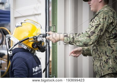 Ship Tour USS Kearsarge (LHD 3) Wasp-class amphibious assault ship: U.S. Navy Seabee personnel helps an unidentified boy put on dive helmet, flight deck. Fleet Week NEW YORK MAY 25 2017.