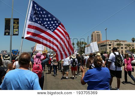 Impeachment March in San Diego, California on July 2, 2017 with large flag and people holding signs.