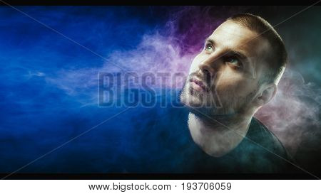 Young handsome white man is admiting puffs of steam from the electronic cigarette.