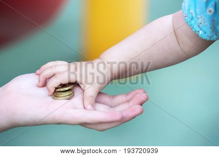 Child's small hand, takes a pile of small money from the palm of your hand