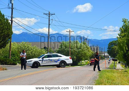 KALISPELL, MONTANA, USA - June 21, 2017: Fire and police officers walk in front of a police barricade near a grass fire