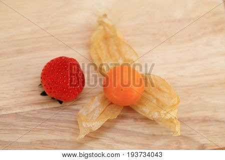 Strawberry and Cape gooseberry fruit on wooden background.