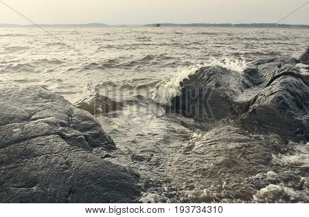 Beautiful summer season specific photograph. Large boulders and rocks together with stormy/rough sea and waves. Lovely lights and summer colors. Marine and ocean environment in summer.