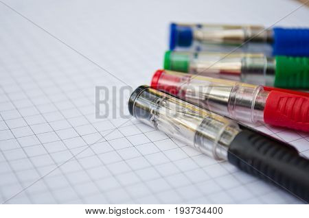 black, blue, red, green pen lying on the notebook