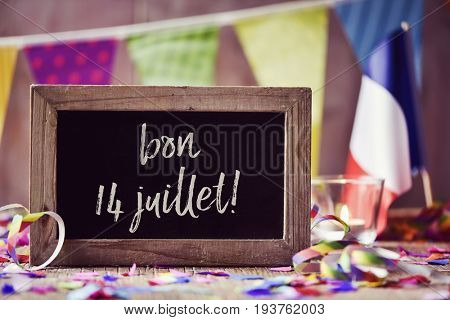 chalkboard with the text bon 14 juillet, happy 14 July, the National Day of France, written in French and a flag of France, on a wooden surface sprinkled with confetti and a garland in the background