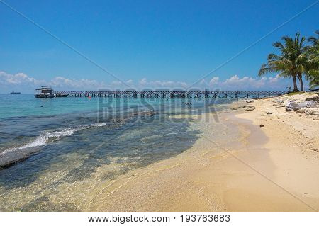 Wooden jetty over the beautiful Rusukan Besar island tropical beach with blue sky and clouds in Labuan Pearl of Borneo,Malaysia.