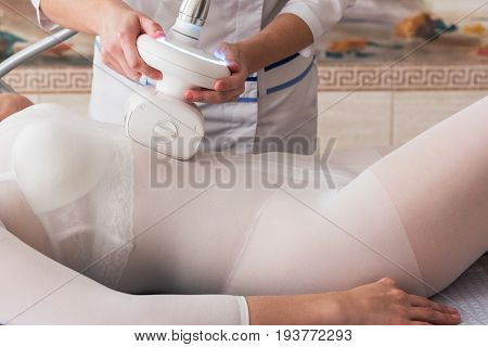 Woman in special white suit getting anti cellulite massage in a spa salon. LPG, and body contouring treatment in clinic.