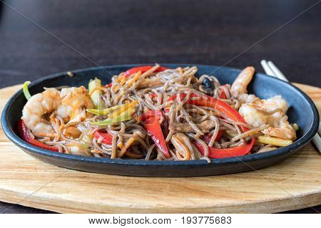 Wok spaghetti with red and green peppers and shrimps. Restaurant food. Served with chinese chopsticks