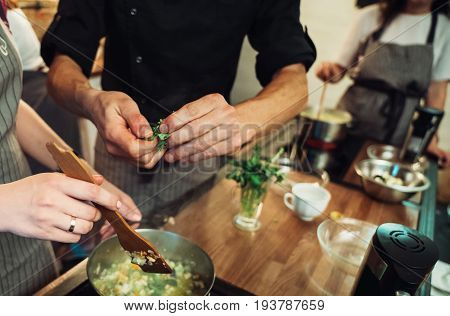 Cooking food together. Hands of a man in the kitchen close-up with greens. Vegan vegetarian dinner.