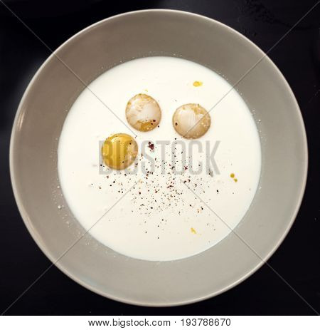 Three broken chicken eggs in a plate with milk and spices. Making an amlet.