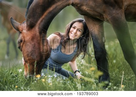 Young woman  with her horse walking on summer field