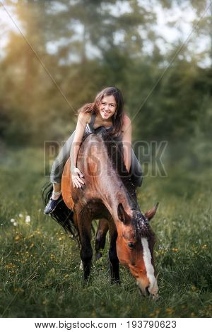 Young woman  with her horse walking on summer field