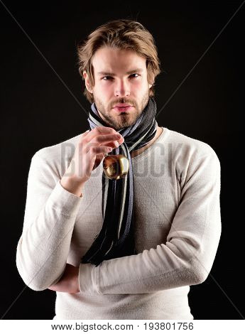 Golden apple and bearded man with scarf and sweater isolated on black background. Concept of priceless goods and confidence