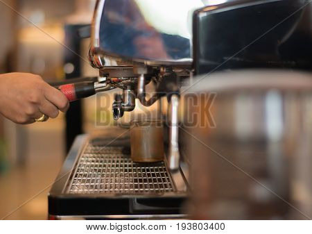 Hand holding a coffee machine in a coffee shop business concept.