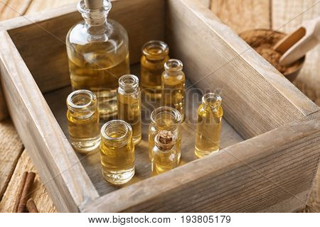 Bottles of cinnamon oil in box on wooden background