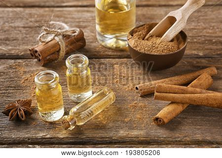 Composition with bottles of cinnamon oil on wooden background