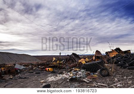 Huge garbage dump of various metal waste and boards against a stormy sky