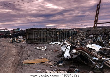 Dirt road in the middle of a garbage dump old car tires against a stormy sky